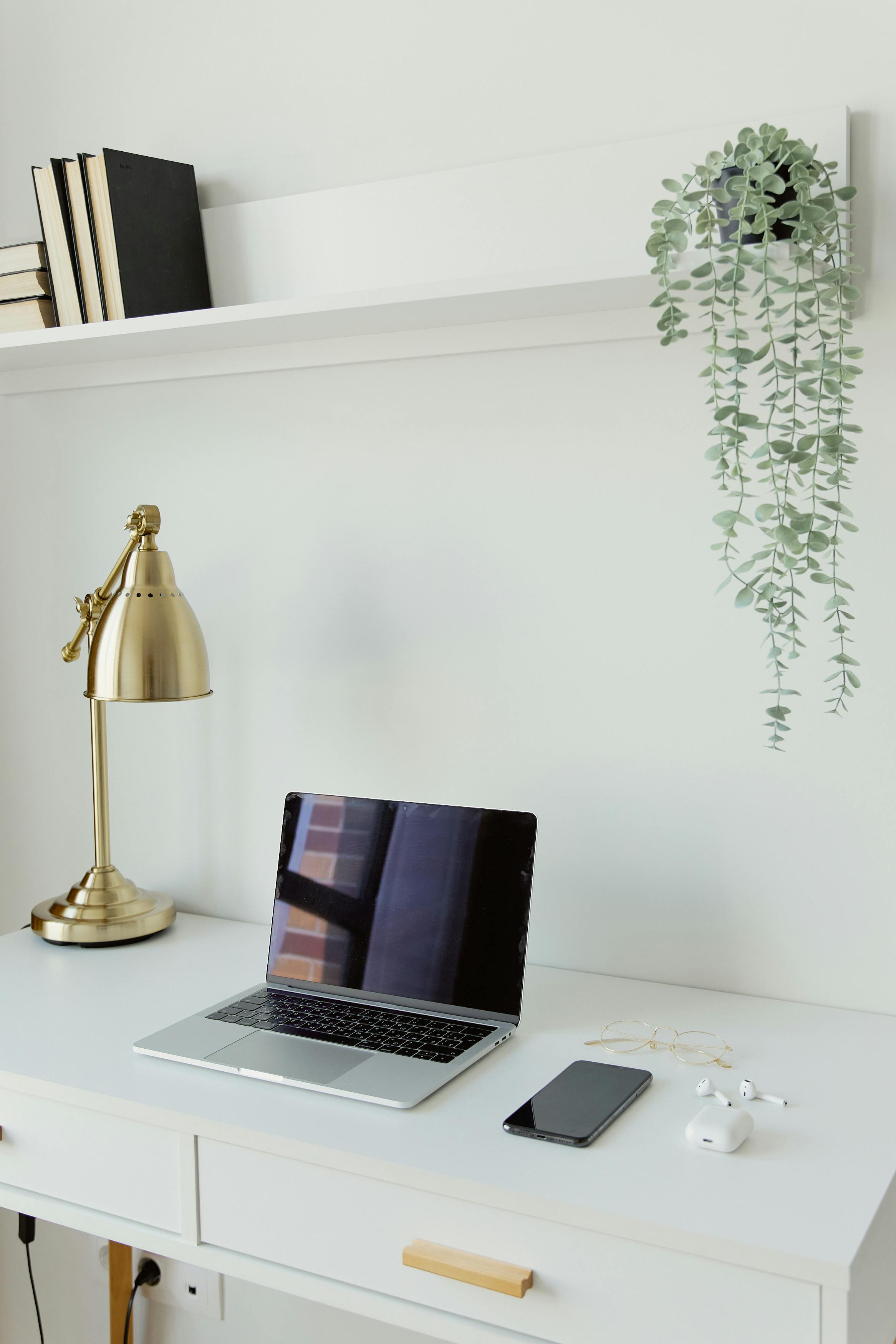 Clean professional workspace with laptop, phone and gold lamp representing a structured quarterly strategy plan accessible across platforms for UK service providers.