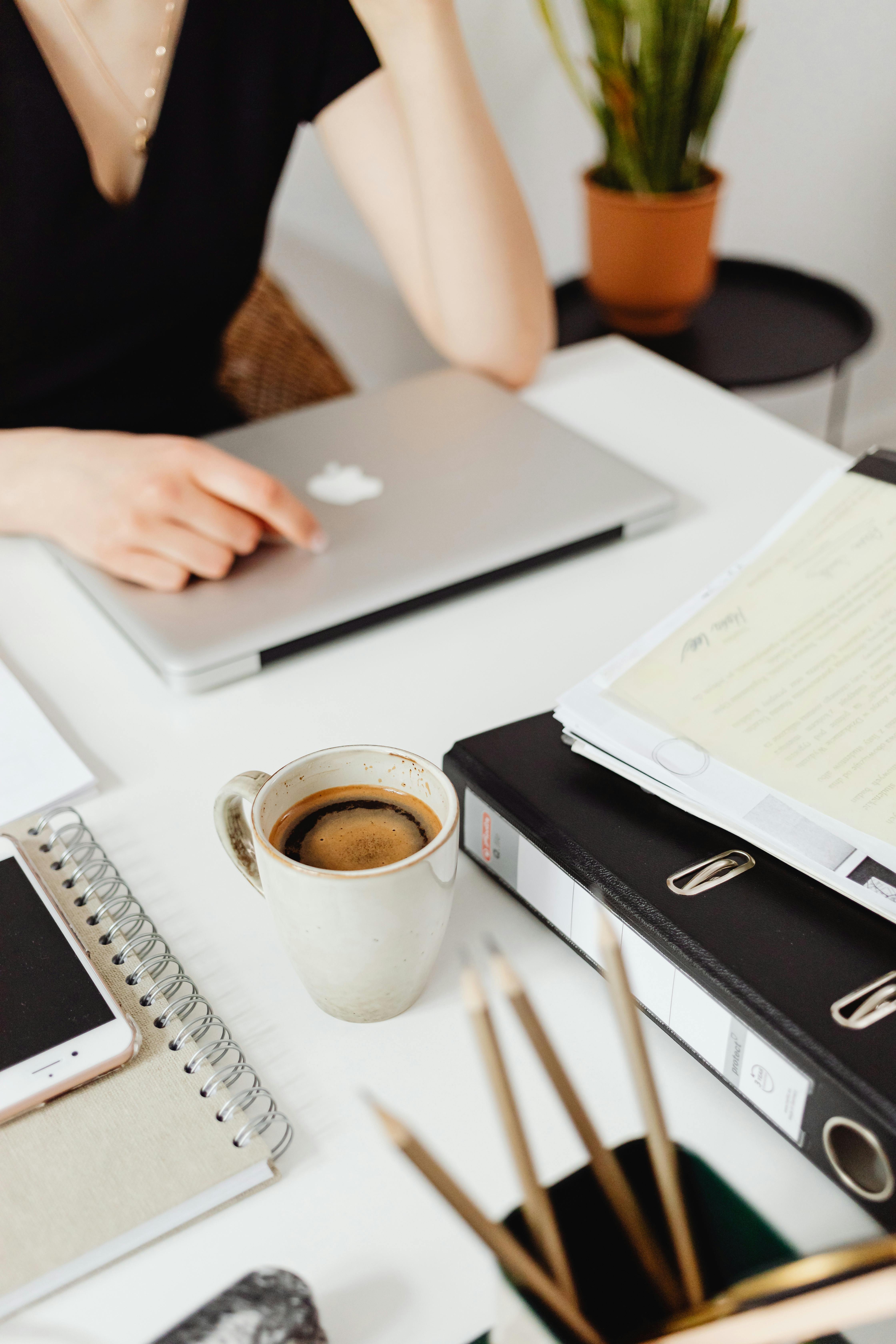 Overhead working shot Established UK service provider working at a laptop managing her business marketing without an automated funnel