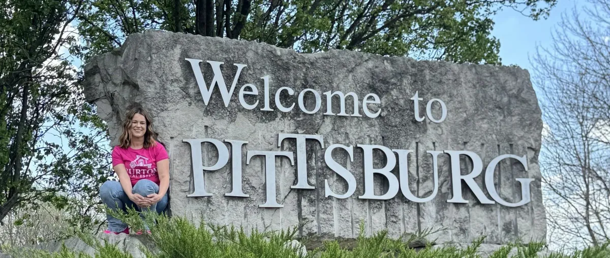 Nikki Burton of Burton Real Estate at the Welcome to Pittsburg sign in Pittsburg, KS