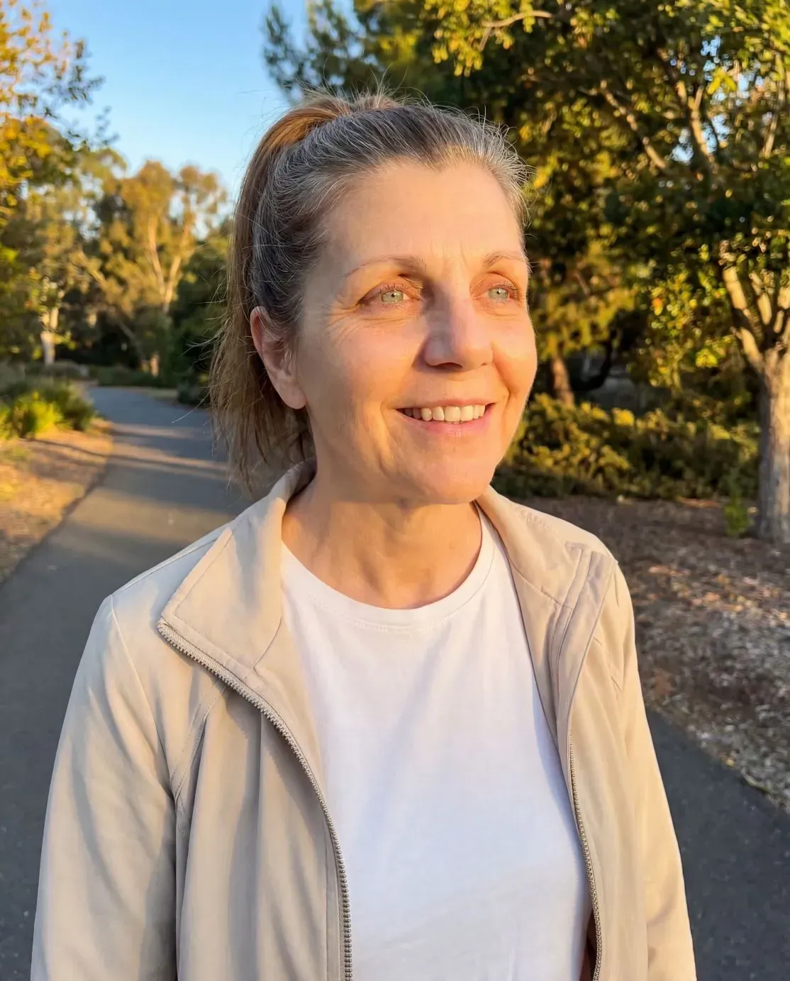 Woman smiling outdoors in golden sunlight feeling energized and calm