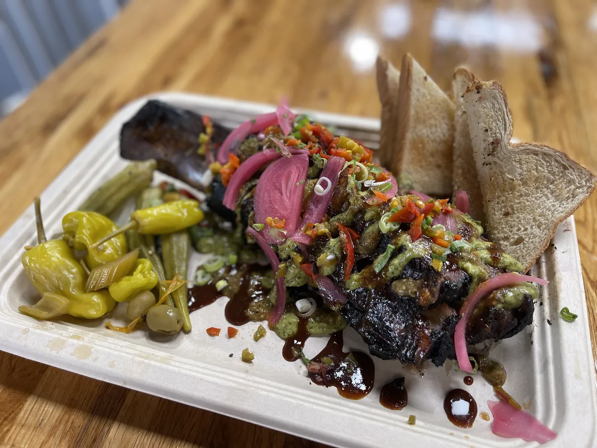 A smoked rib with pickled peppers on a tray