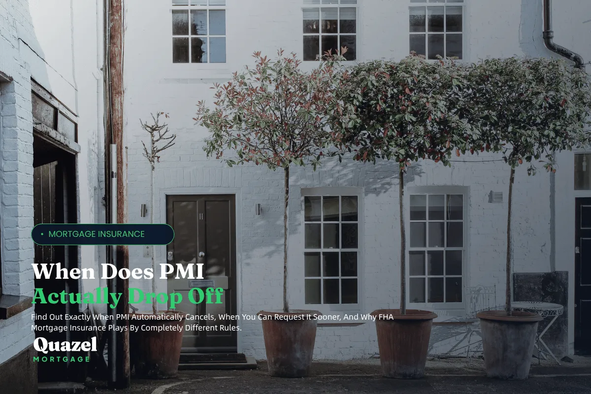 A white two story brick building with 5 windows and a brown door. Three tall ornamental trees in pots out front.