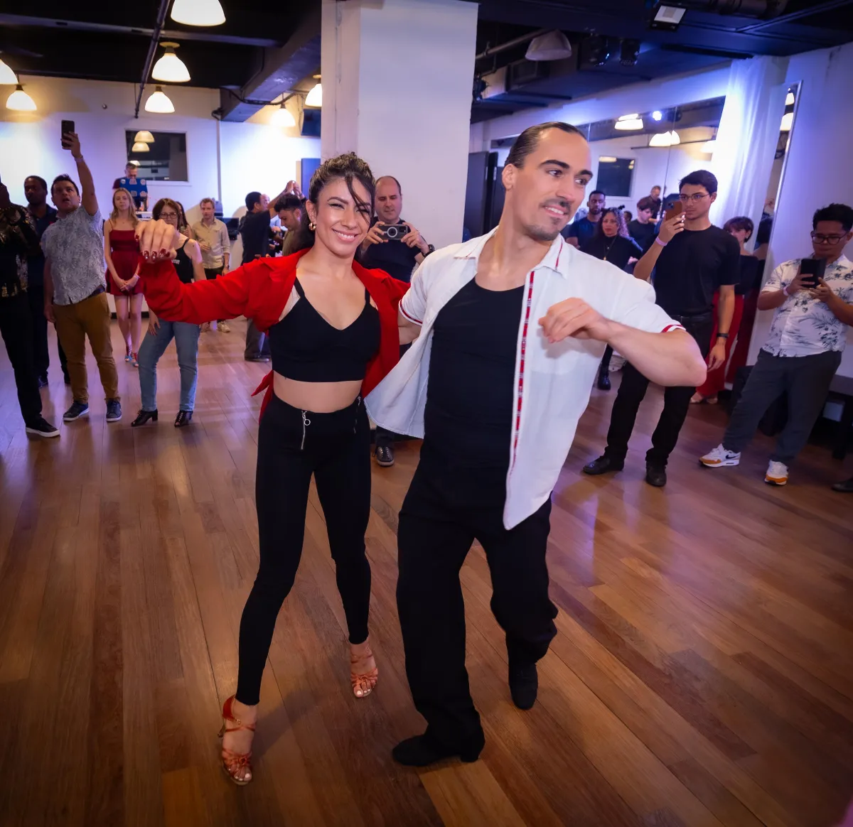 Hunter Houde showing a salsa move with his partner in front of the class