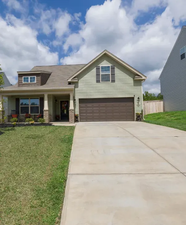 Suburban home with spotless concrete driveway under a blue sky