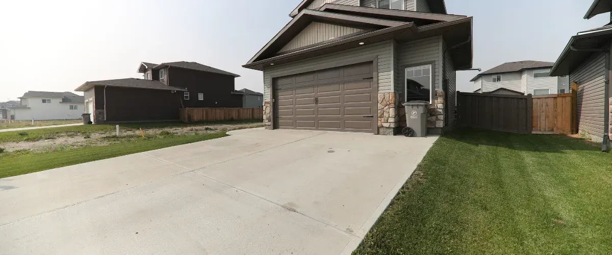 Suburban home with spotless concrete driveway under a blue sky
