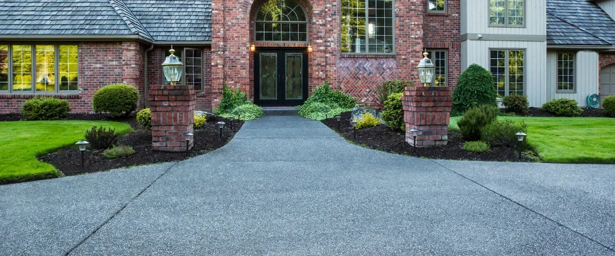 Suburban home with spotless concrete driveway under a blue sky