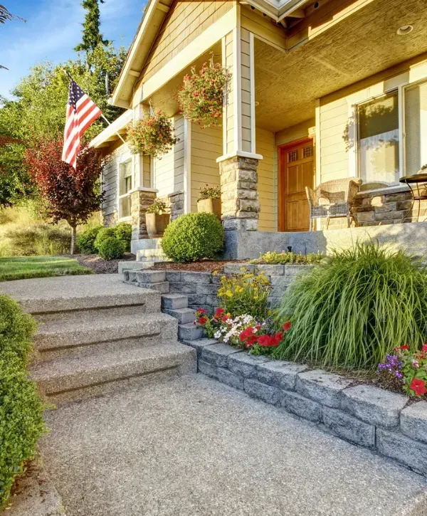 Beautiful front yard of a suburban American home with landscaping, flowers, and an American flag