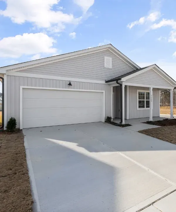 Modern single-story home with gray siding, front porch, and double garage under a blue sky