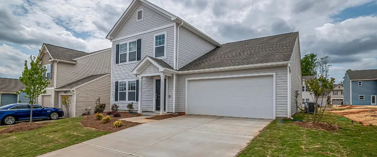 Modern two-story family home with clean siding, wide driveway, and landscaped front yard