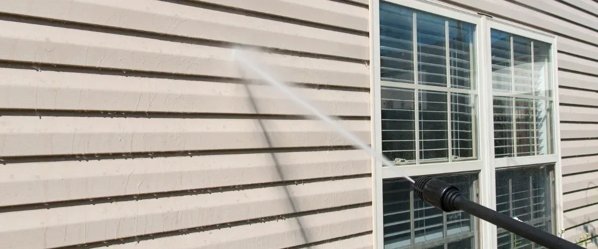 Power washing vinyl siding on house exterior removing dirt and mildew