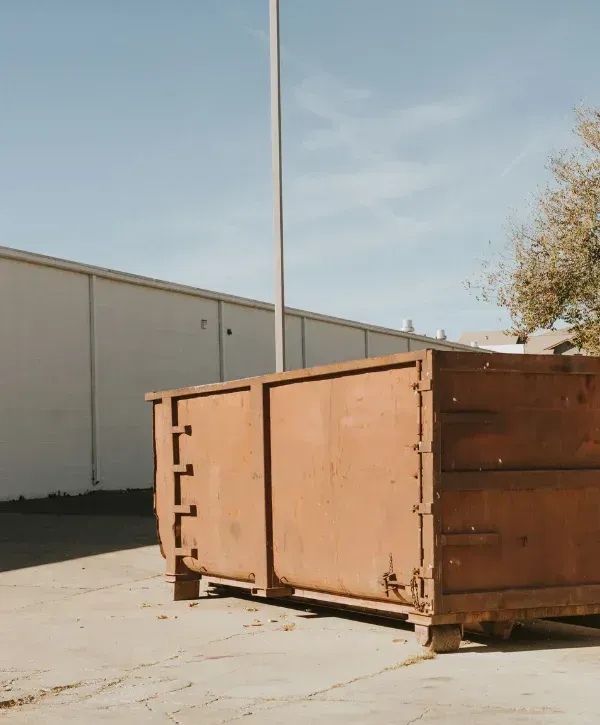 ndustrial dumpster on concrete pad behind commercial building