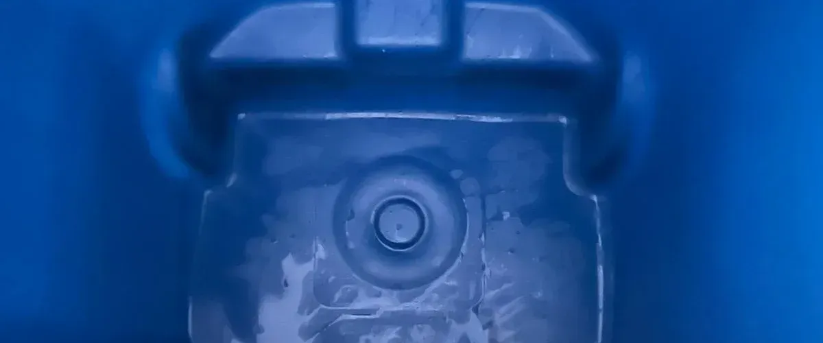 A close-up, abstract view of a blue plastic molded object with a circular indentation.