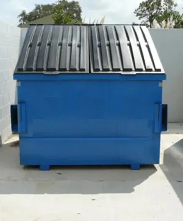 A large blue commercial dumpster with black plastic lids, standing on concrete outdoors.