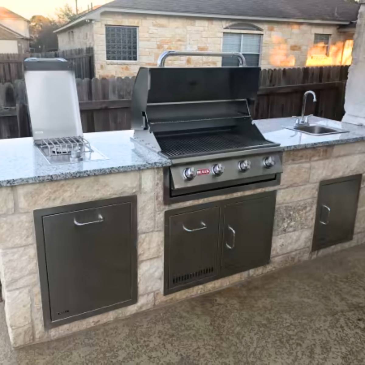 After: Austin backyard transformation featuring stone outdoor kitchen and grill