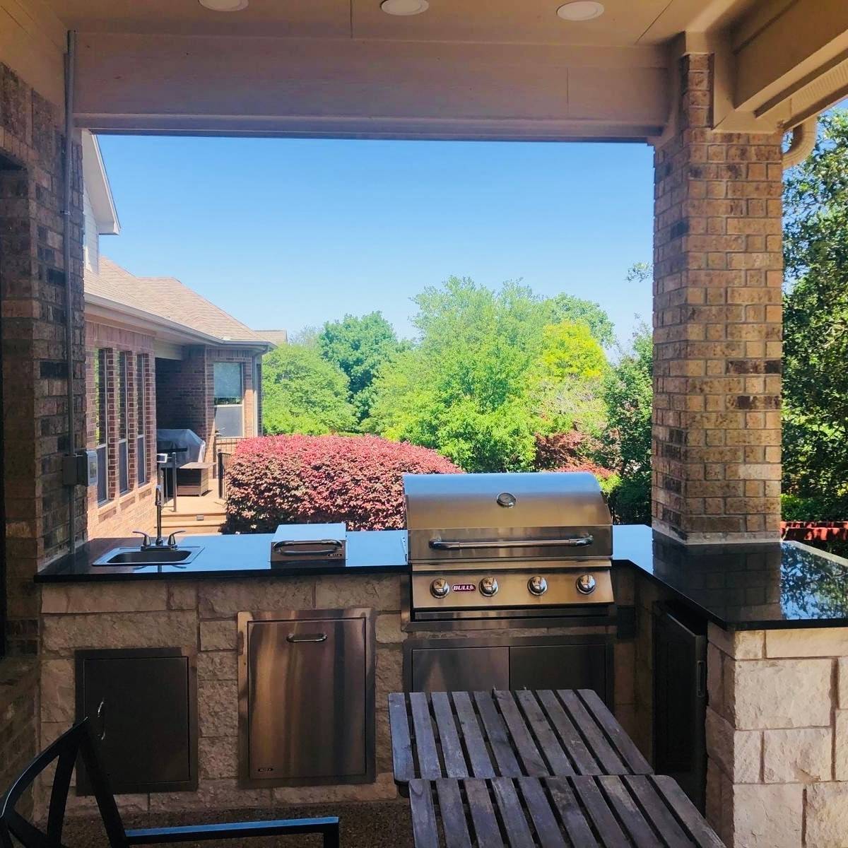 After: covered Austin deck with L-shaped outdoor kitchen, bar seating, and fridge