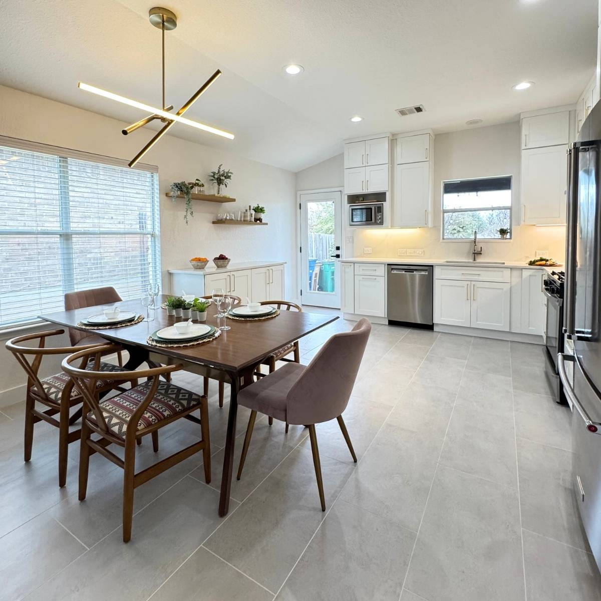 After: Open concept Austin kitchen transformation with waterfall counters, stainless appliances and statement lighting