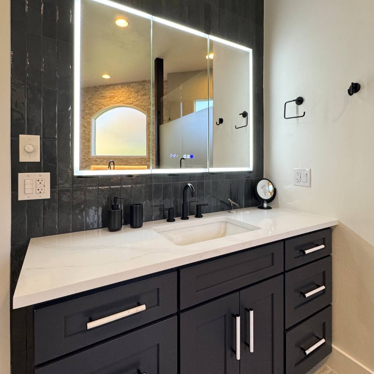 Modern dark blue bathroom after remodel with vanity, quartz countertops & custom tile wall in Austin