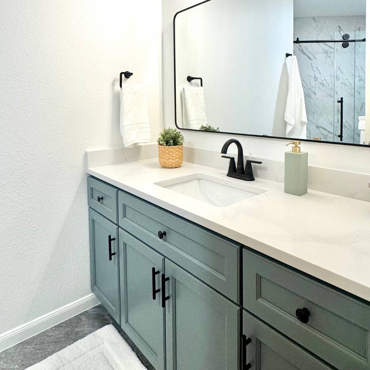 After: remodeled bathroom with new blue-green vanity, mirror, and black fixtures in Austin