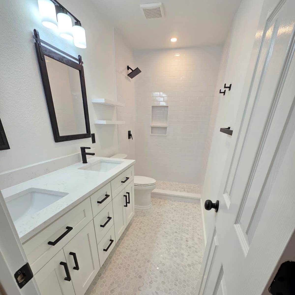 Bright bathroom after makeover with open layout, new vanity, stone countertop, and custom tile 