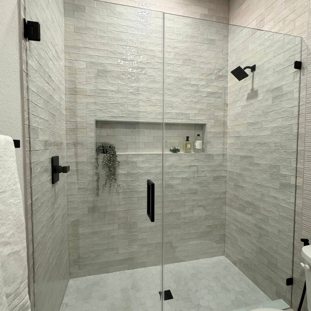 Updated bathroom after Jack & Jill remodel with custom tile shower and glass doors and black fixtures in Austin