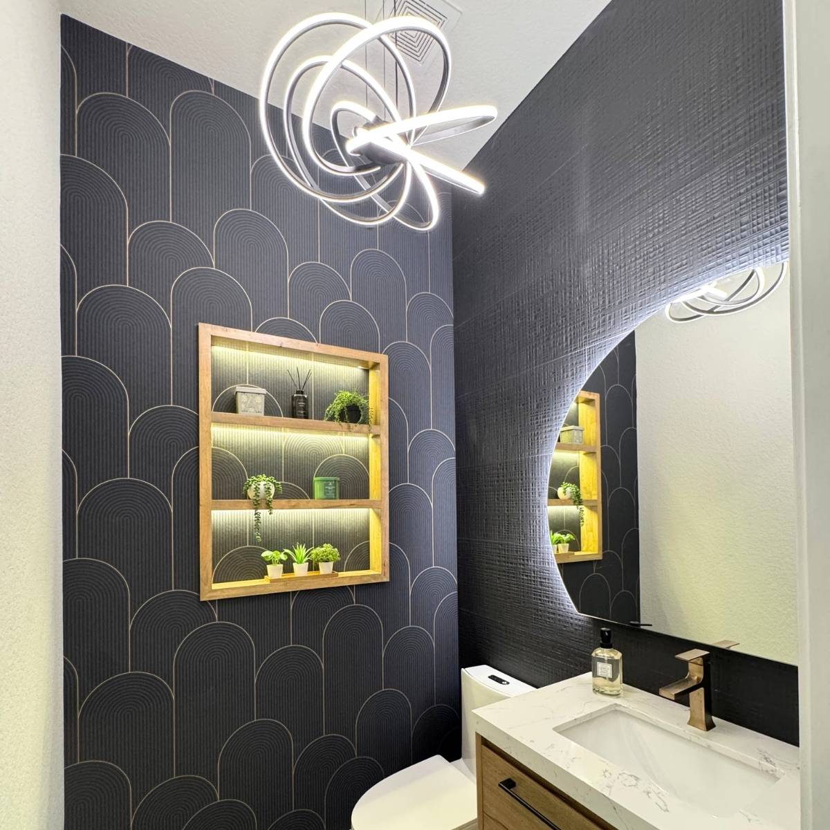 Updated powder room in Austin after remodel with new floating wood vanity, backlit mirror, and statement lighting