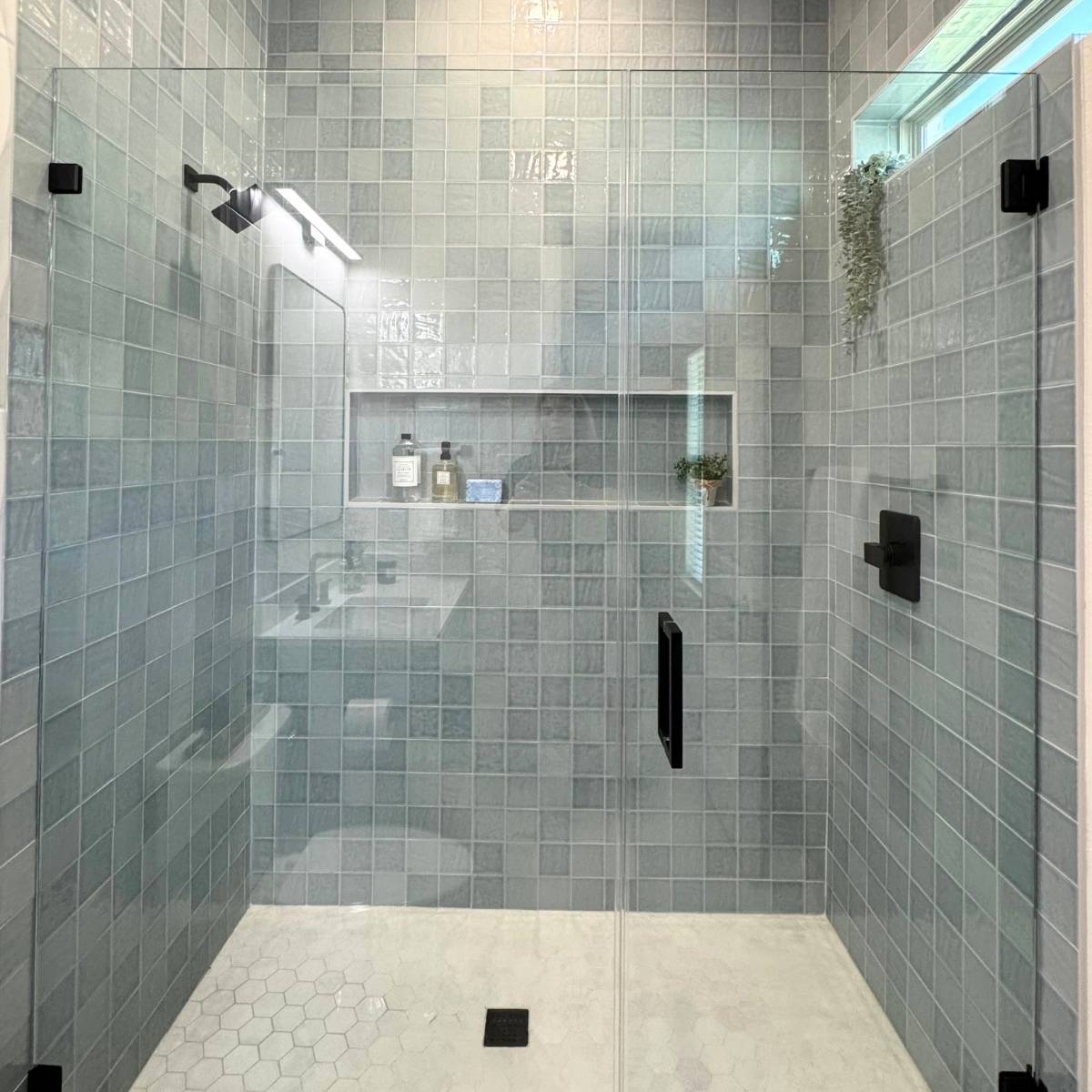 Modern bathroom after Jack & Jill remodel featuring custom glass shower with custom blue tone tile and black fixtures
