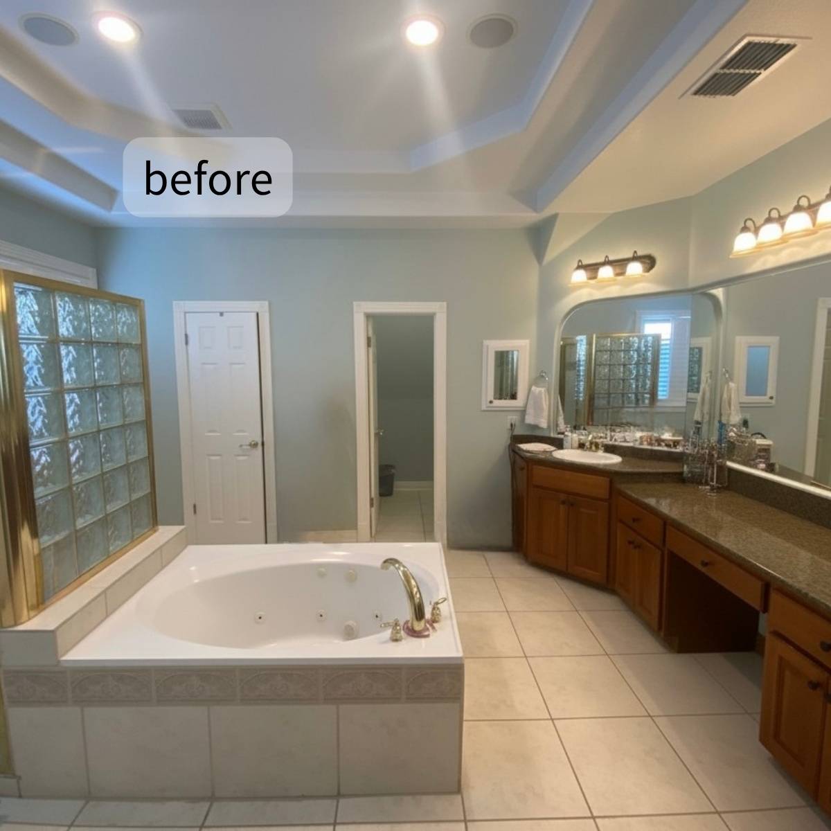 Primary bathroom before makeover with outdated shower, built in tub and dark vanities