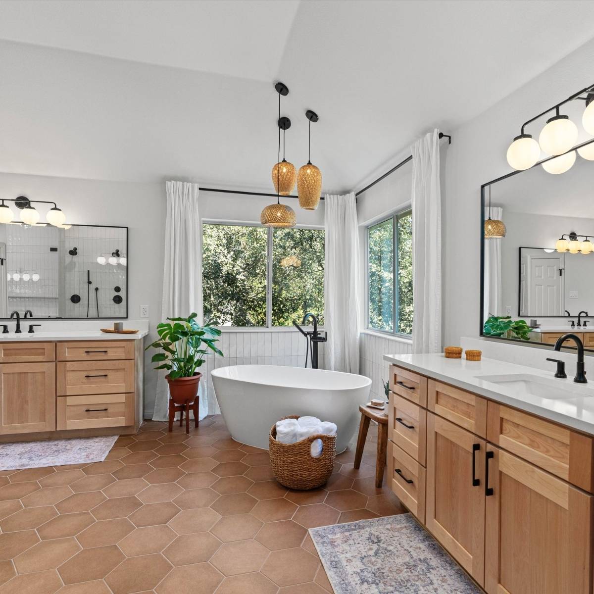  Modern bohemian style bathroom after remodel with new custom vanities, free-standing tub, and statement lighting in Austin