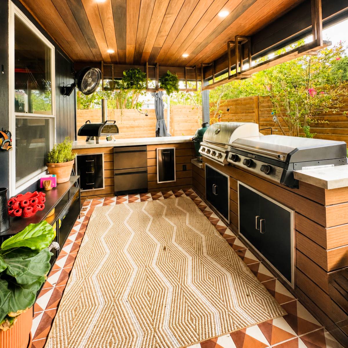 Modern outdoor kitchen remodel in Austin, Texas featuring a custom covered patio with a stained wood ceiling, and built-in appliances with custom concrete countertop