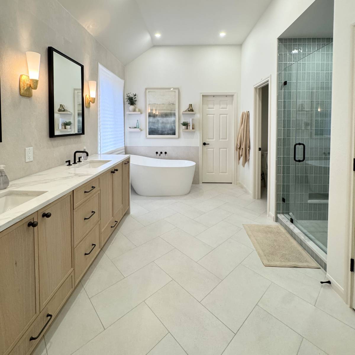 Luxury primary bathroom remodel in Cedar Park, TX featuring a custom white oak double vanity, quartz countertops, freestanding soaking tub, frameless glass walk-in shower, and large-format porcelain tile by ATX Custom Remodel.