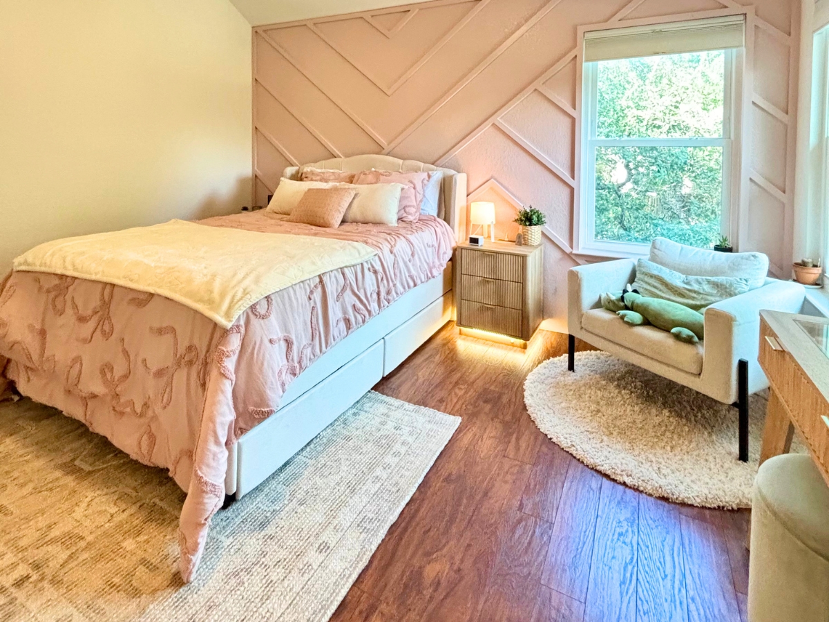 Completed teen bedroom remodel in Round Rock Texas featuring pink geometric accent wall and hardwood floors.