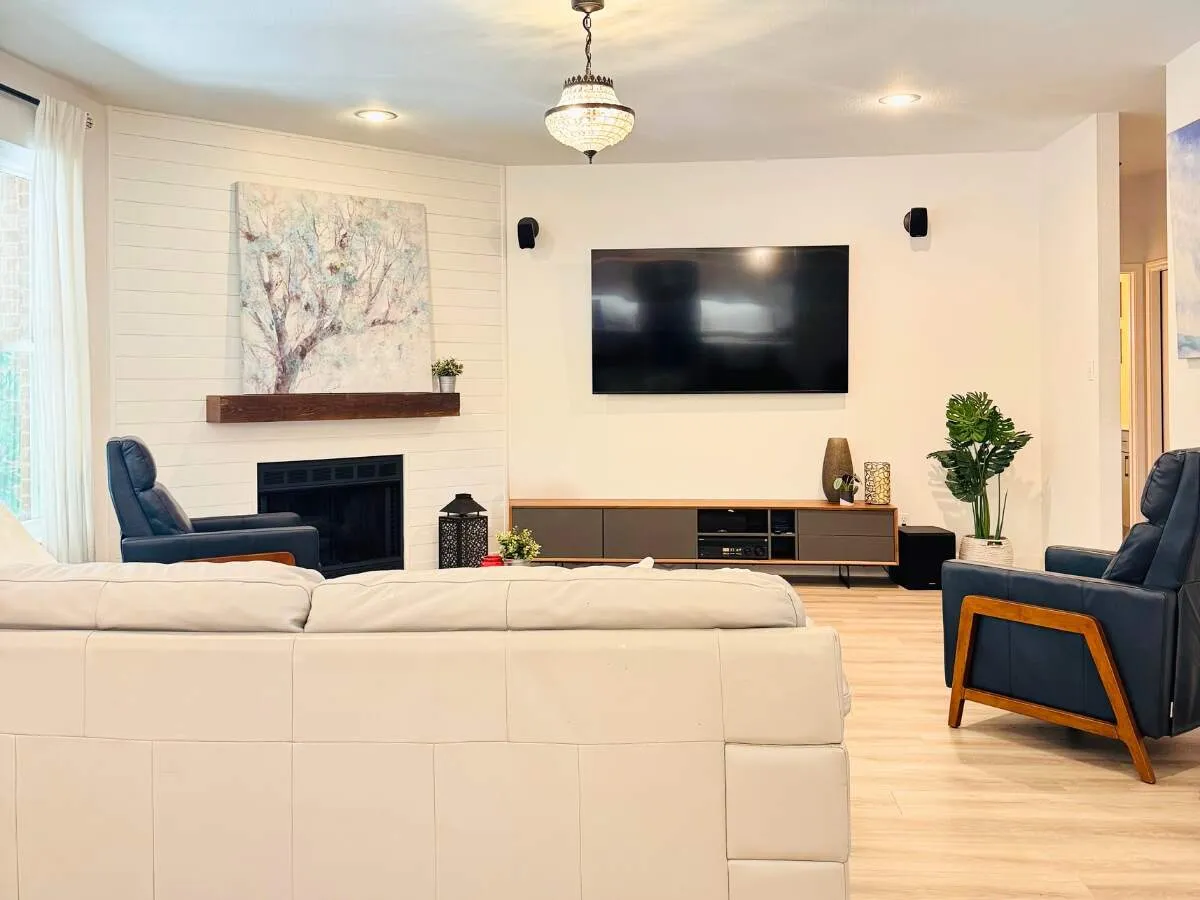 Austin living room remodel featuring a modern white shiplap fireplace with wood mantel, luxury vinyl plank flooring, and contemporary entertainment center by ATX Custom Remodel.