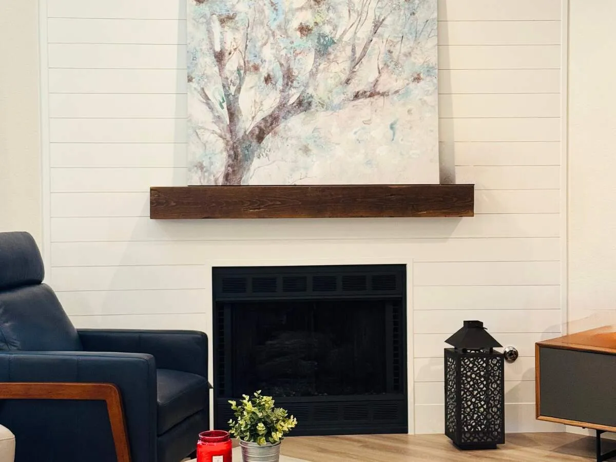 Austin fireplace and flooring remodel with a white shiplap fireplace, wood mantel, and warm oak luxury vinyl plank flooring.