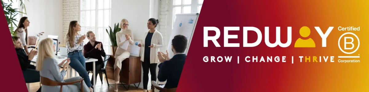 A small group of people are listening to  lady in front of a flip chart, she is speaking