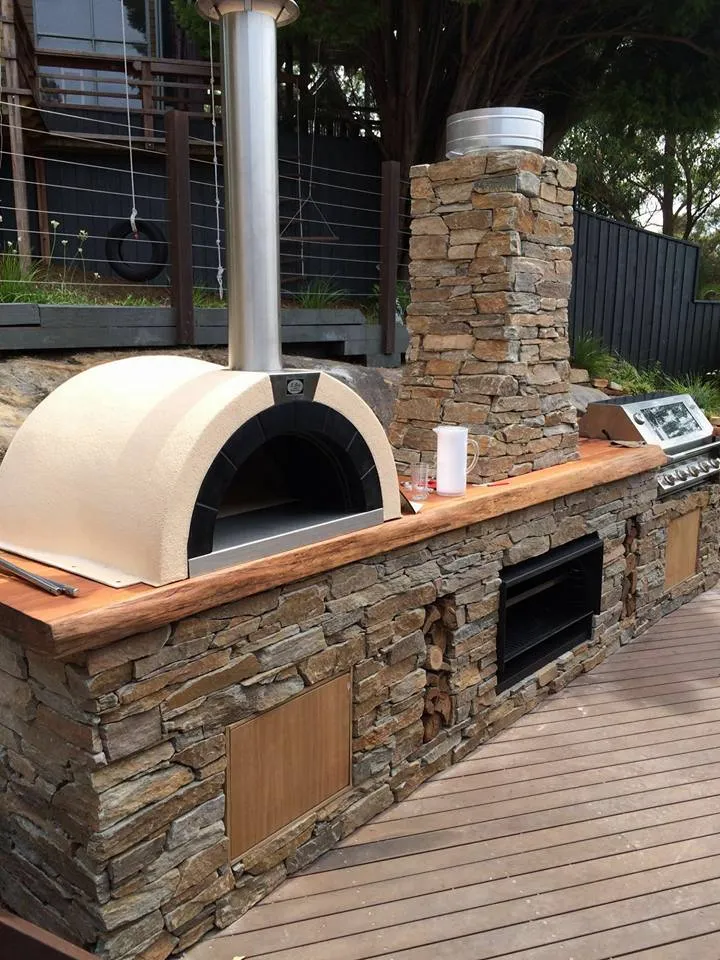 Stacked stone outdoor kitchen with a pizza oven, built-in barbecue and hardwood benchtop