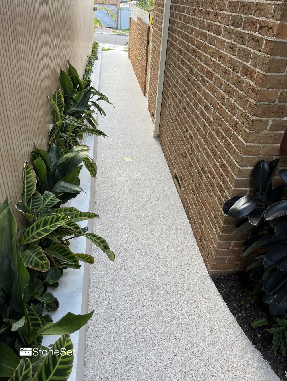 Resin-bound pathway curving past a modern home
