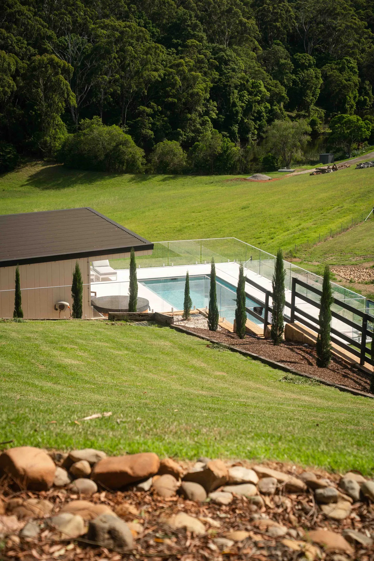 Pool terrace with glass fencing set into a manicured lawn