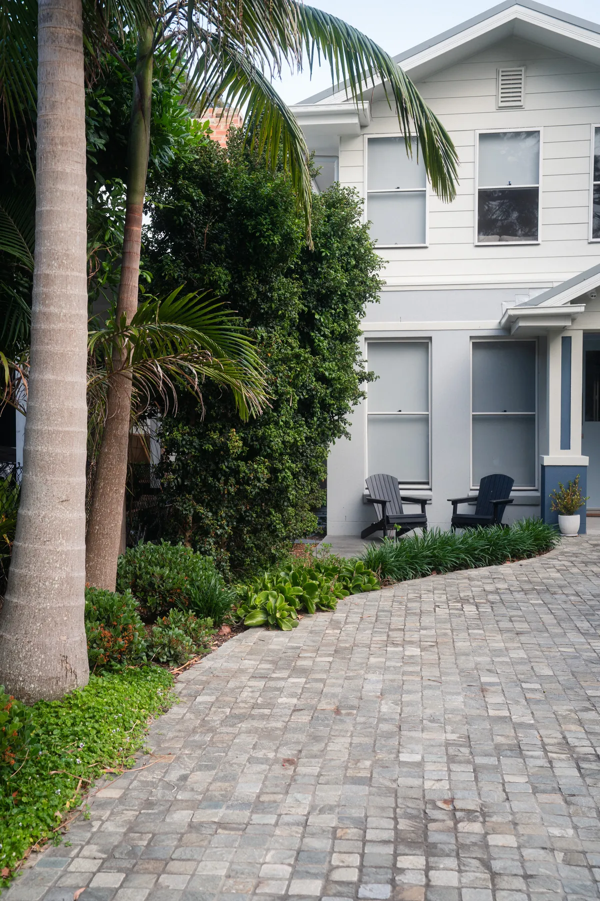 Paved courtyard and garden beside a white weatherboard home