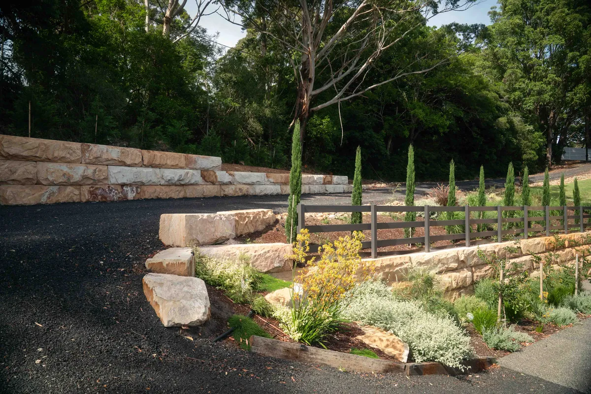 Sandstone boulder retaining terraces with grasses and cypress