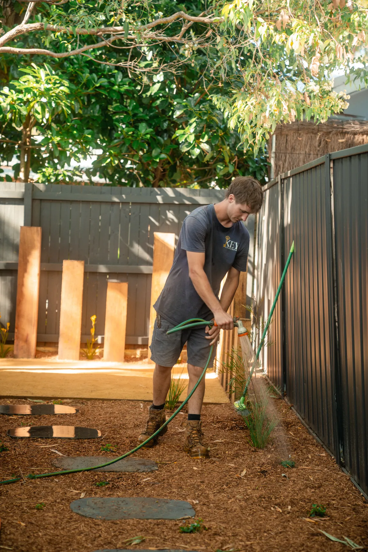 A Key Landscaping crew member planting out a new garden bed beside a timber screen