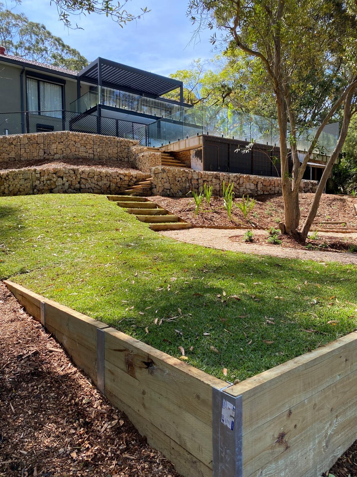 Timber sleeper wall and lawn below terraced gabion walls and stairs