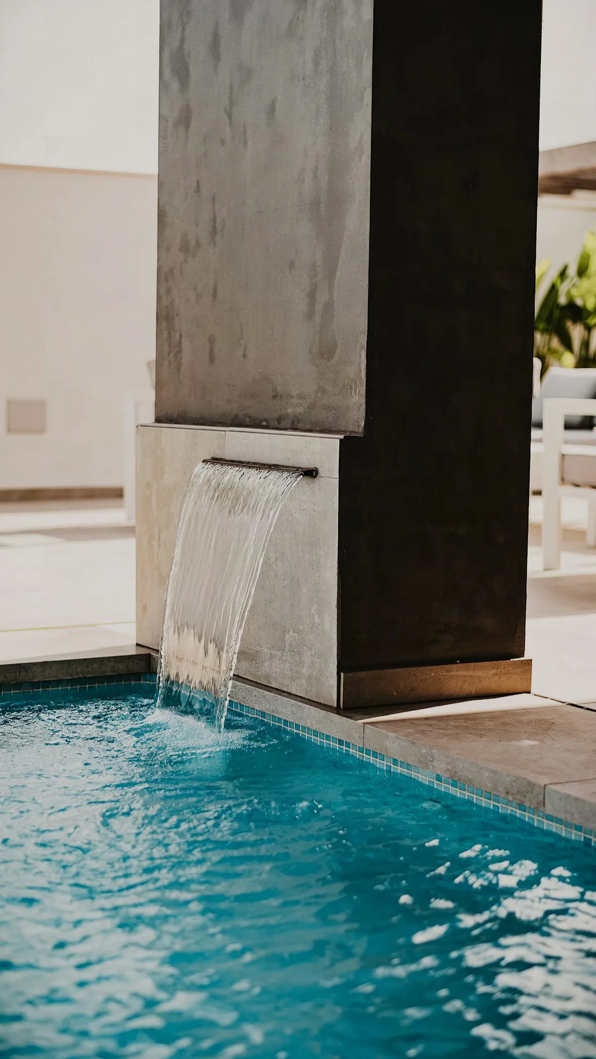 Stone water feature pouring into a tiled concrete pool