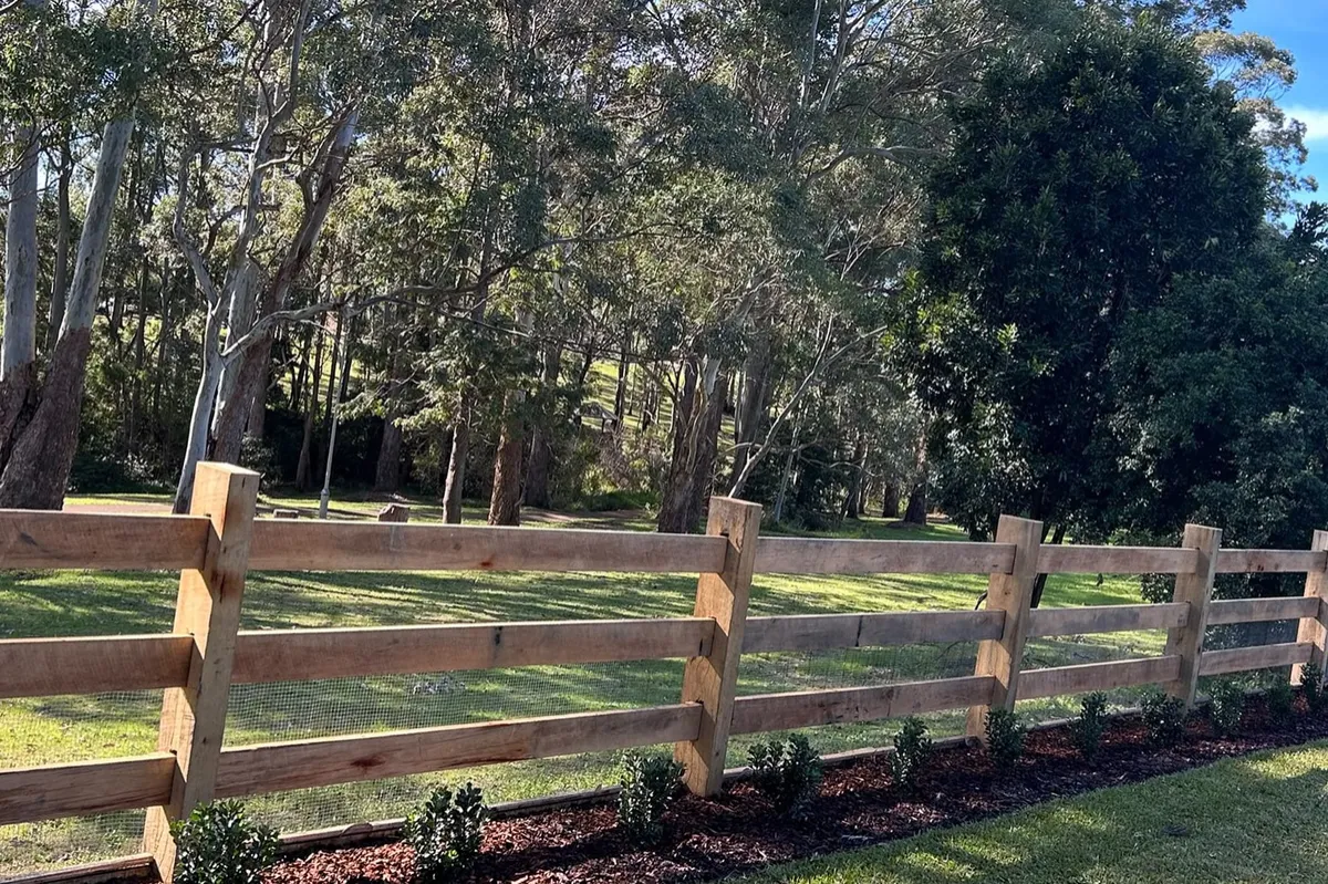 Hardwood post-and-rail fence above a new planted bed