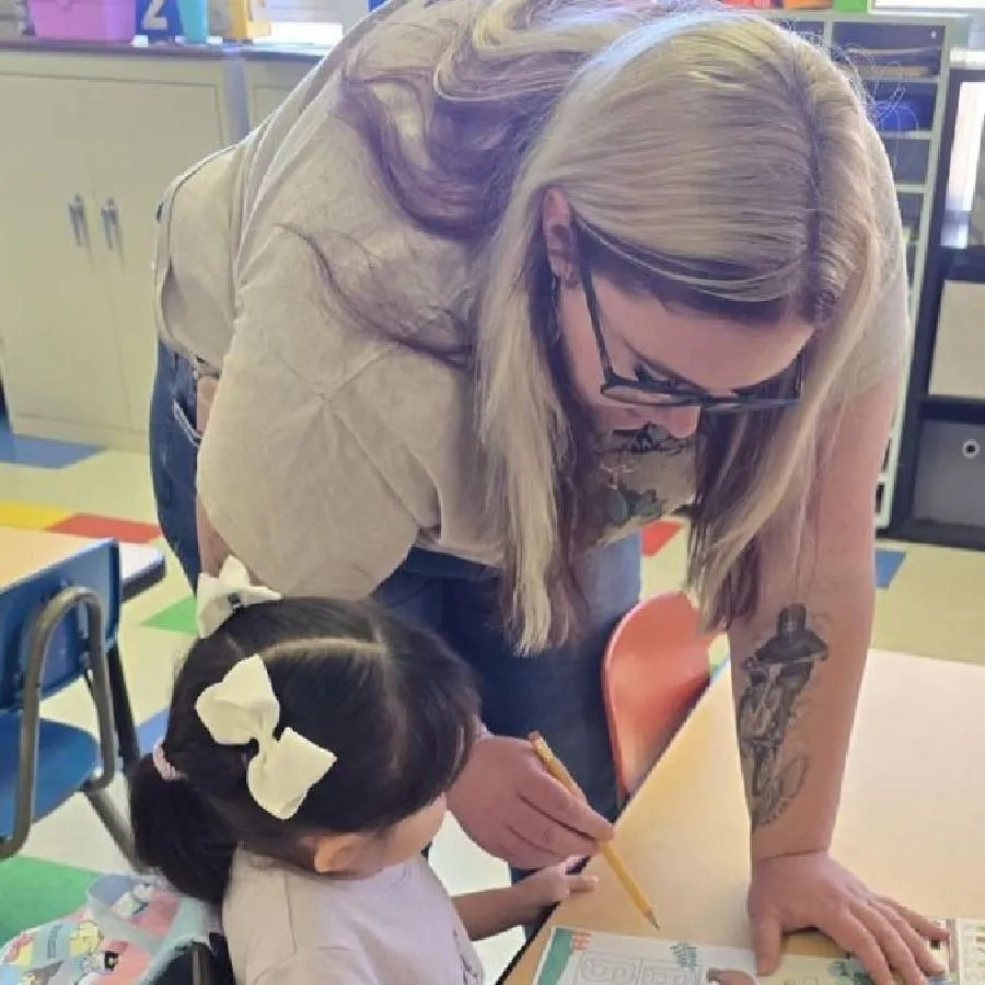 Girl stretches to the side while watching teacher on large screen TV