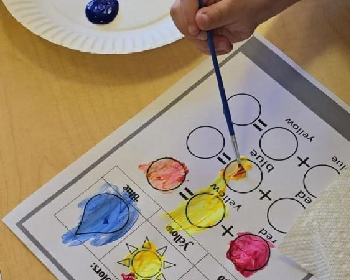 Boy picks paper out of different colored liquids