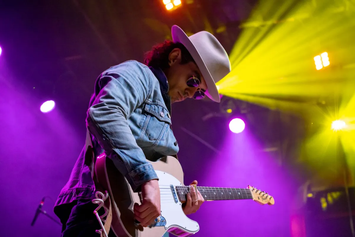 A musician plays guitar on stage at a concert in Vancouver.