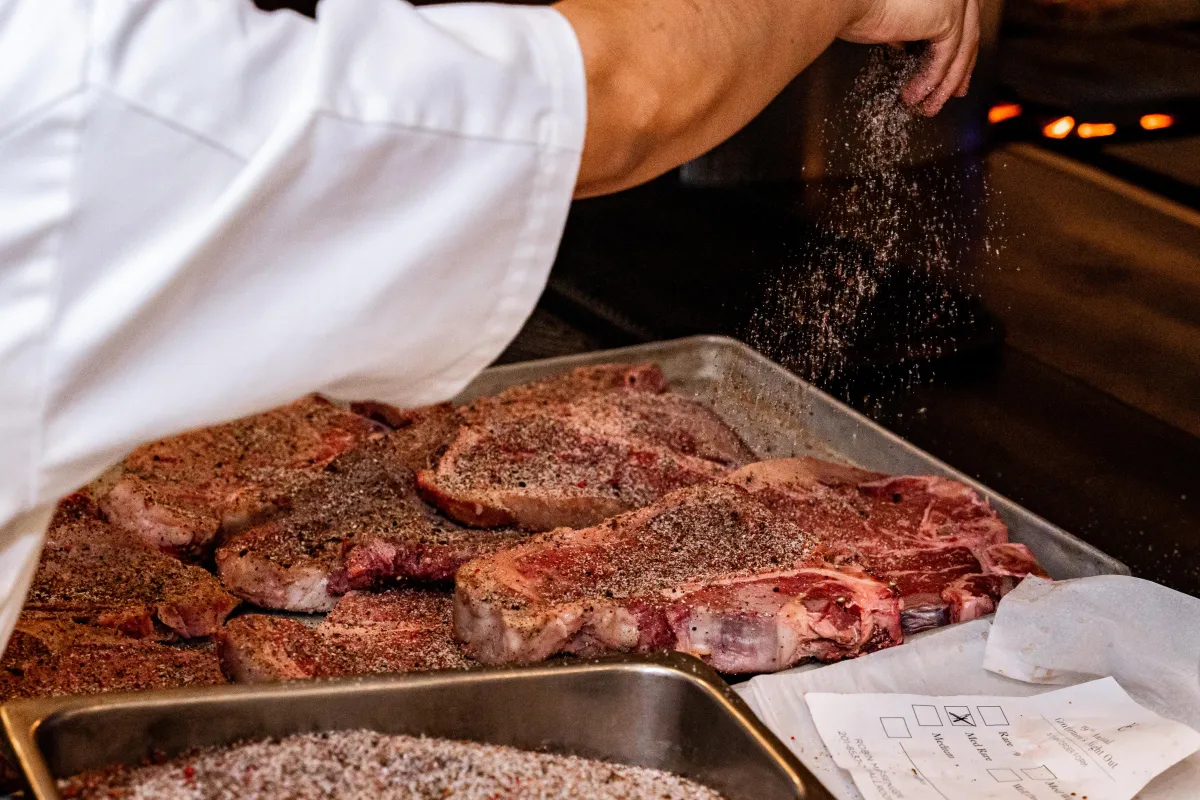 A chef seasons some steaks before they go on the grill at the Vancouver Club.