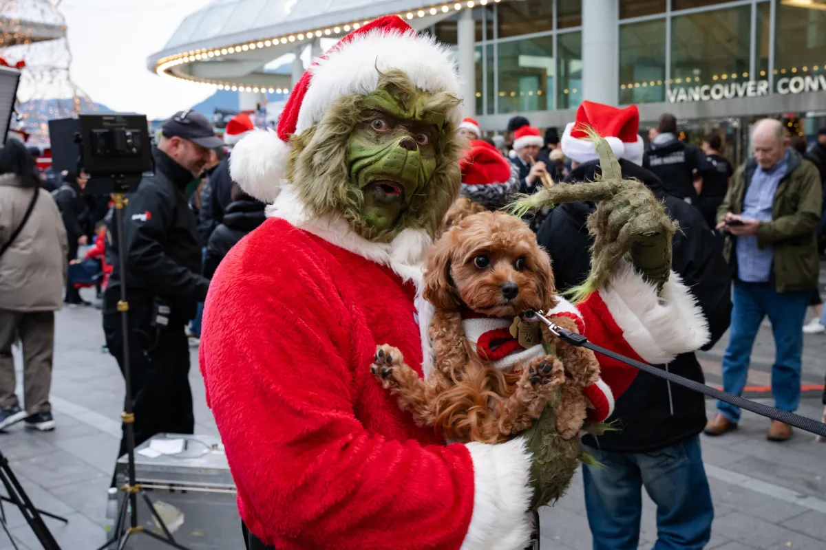 A man dressed as the grinch holds a dog at Vancouver Fire Departments annual toy drive supported by CBC.