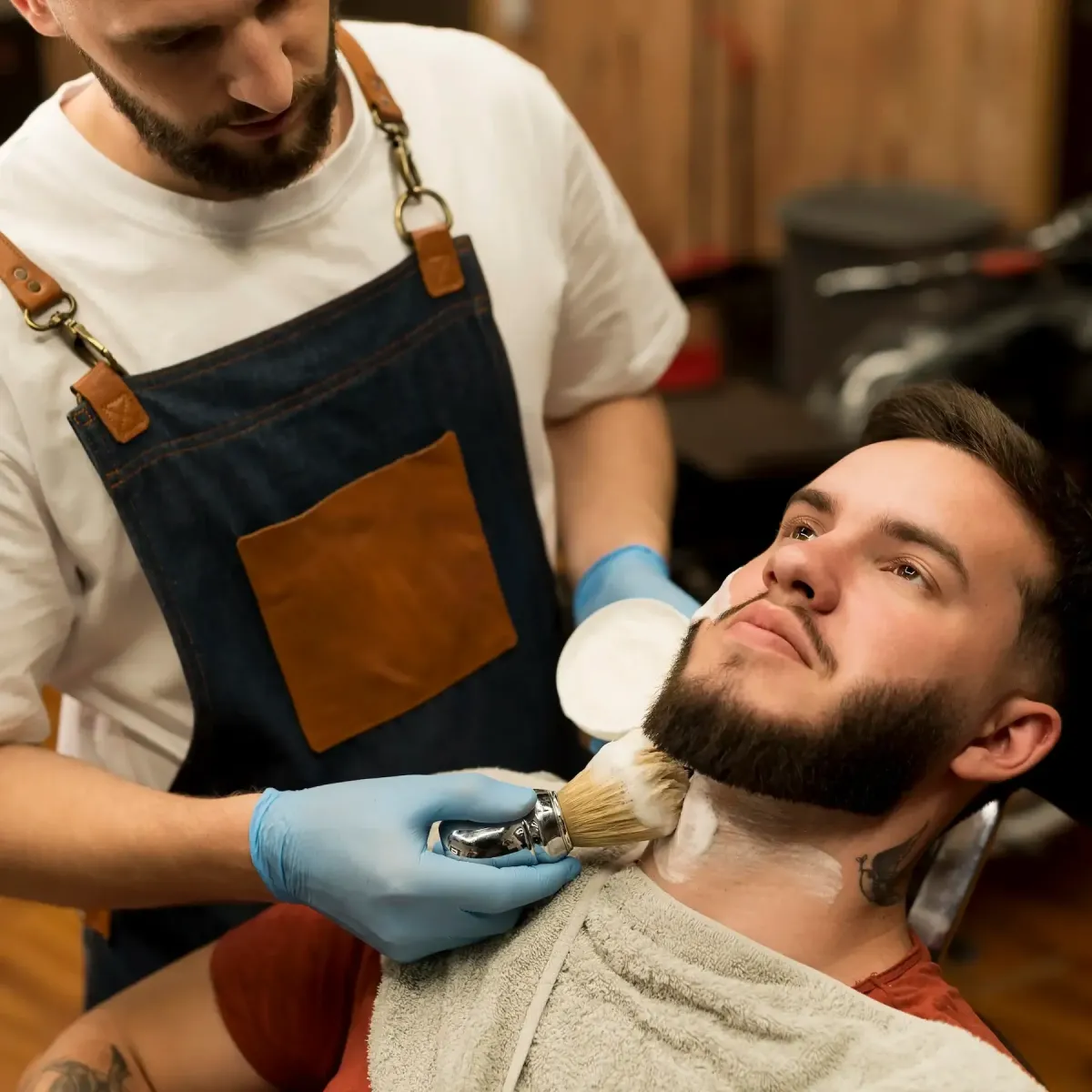 Barber at Scuttlebutt Barbershop in Portsmouth, NH applying hot lather to a client’s neck during a traditional straight razor shave.