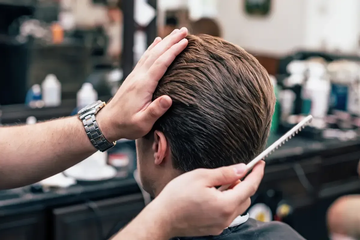 Barber styling a client’s hair with a comb and steady hand at Scuttlebutt Barbershop near Greenland, NH.
